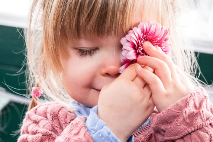 Lachendes Kind auf einer Blumenwiese bei einem Fotoshooting